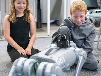 Boy and girl watching and smiling at robot dog
