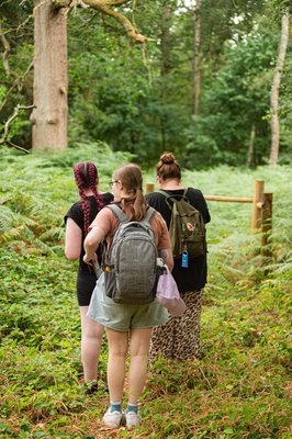 3 women stood in a woodland area wearing backpacks