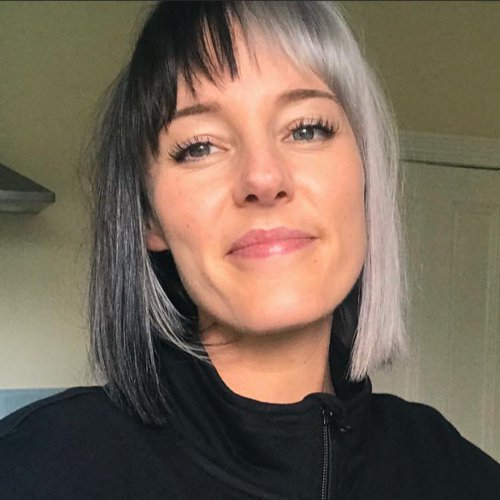 A headshot image of a young woman smiling wearing a black jumper.
