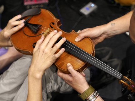 Four hands holding a violin
