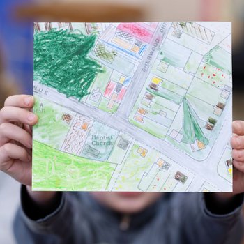 Child holding their art map to the camera