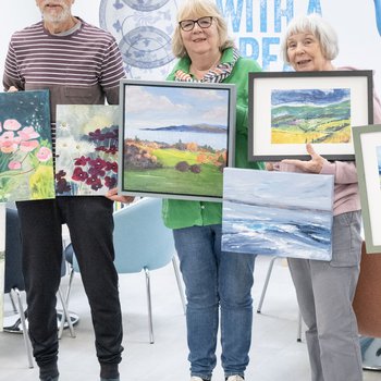 a group of older men and women showing the paintings that they have created