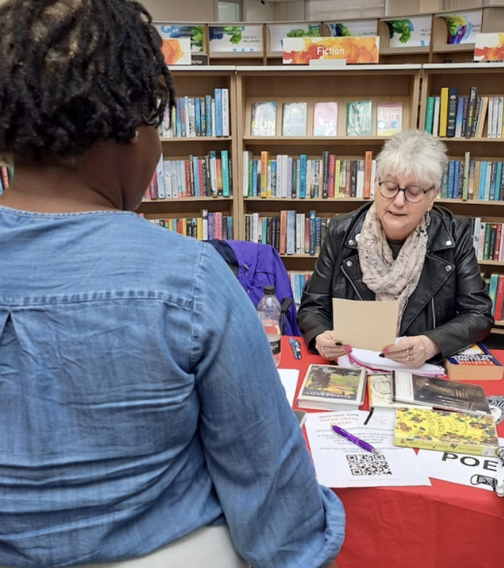 A poet reads a bespoke poem to a visitor to the library.