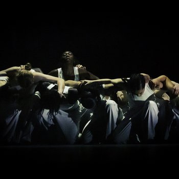 Group of dancers kneeling together with their arms linked