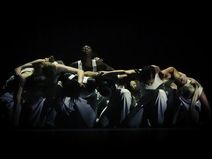 Group of dancers kneeling with their arms linked together