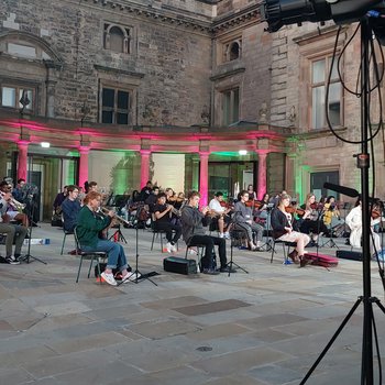 Young musicians playing instruments in an open air event.