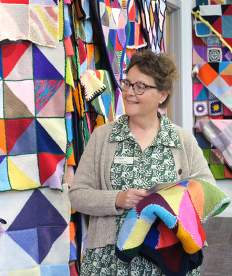 Sarah Baker holding a care squares blanket at the exhibition at Mansfield Central Library