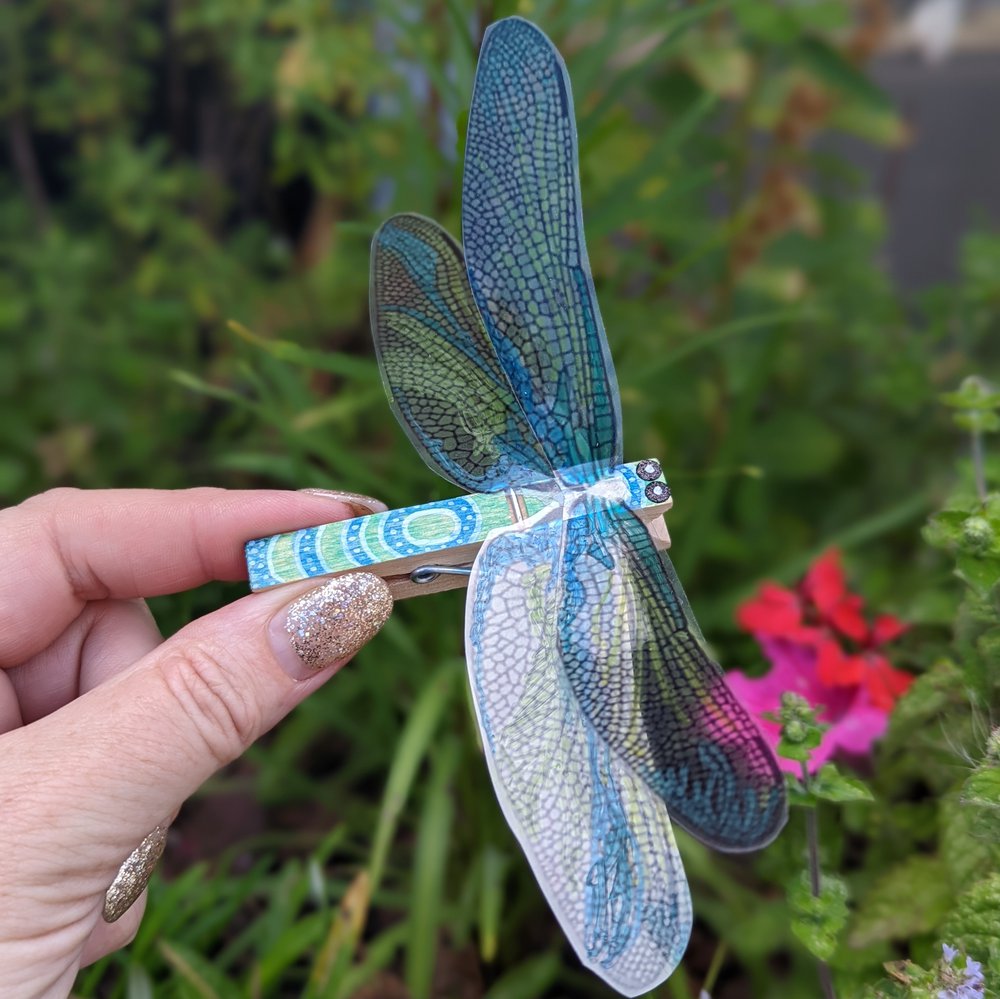 A bright blue dragonfly made out of a peg.