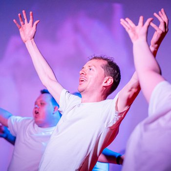 People wearing white T shirts raising both arms.
