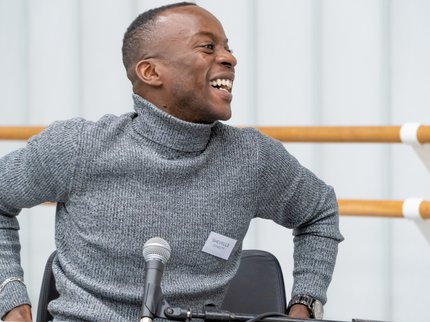 Man smiling  sitting in a chair, part of the panel event.