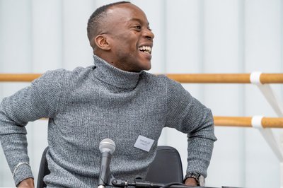 Man smiling  sitting in a chair, part of the panel event.