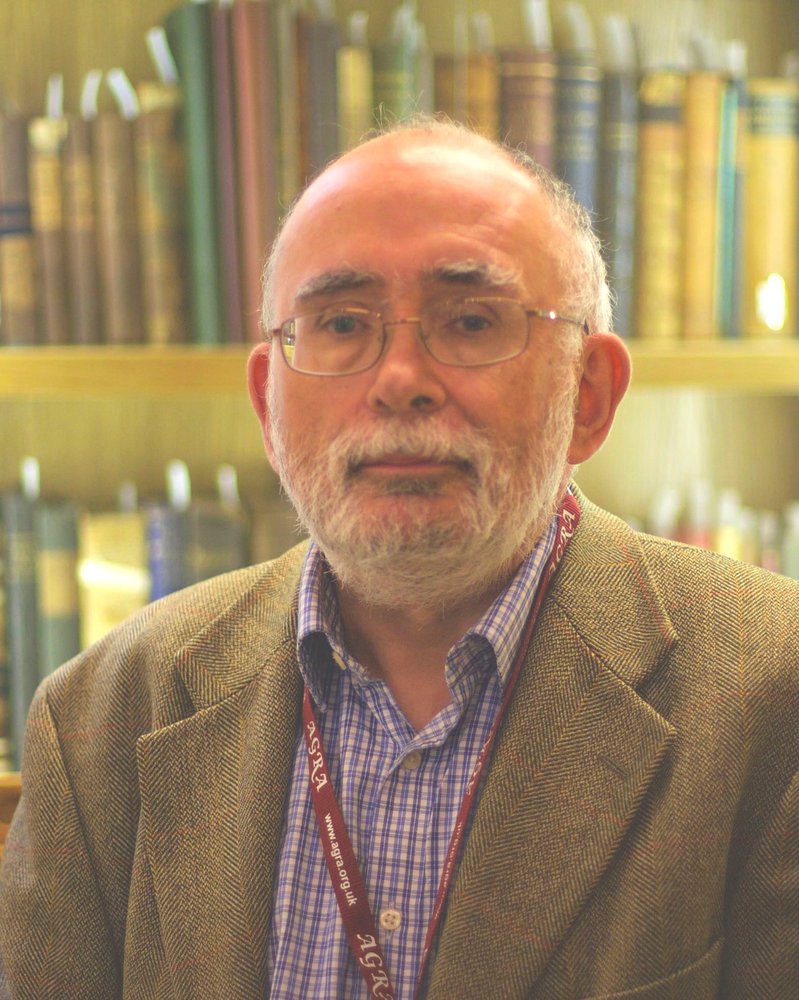 Photograph of Simon Fowler in front of shelves of books