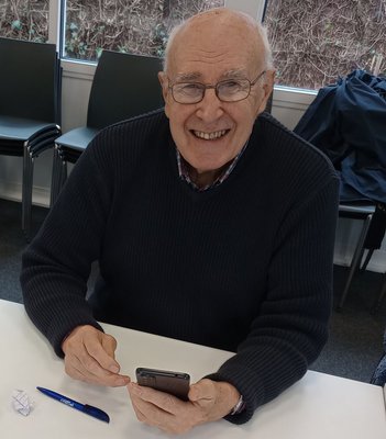 Older male learner using a smartphone and smiling