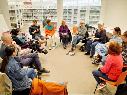 A group of people sit in chairs in a circle in the library