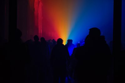People standing in a dark church with lighting showing rainbow colours flooding up to the ceiling.