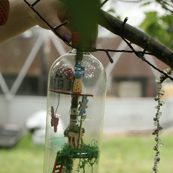 Photo of a story bottle - a plastic bottle containing objects to create a scene - being hung in a tree