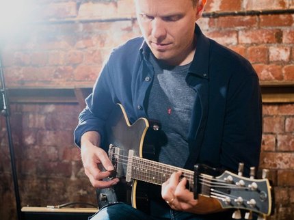 Photograph of guitarist Stuart McCallum performing seated