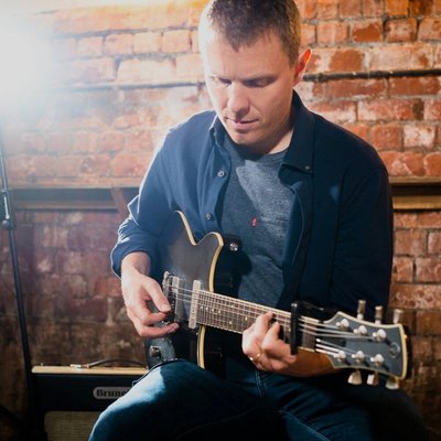 Photograph of Jazz guitarist Stuart McCallum playing seated