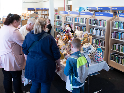 A family stood browsing a market stall in a library