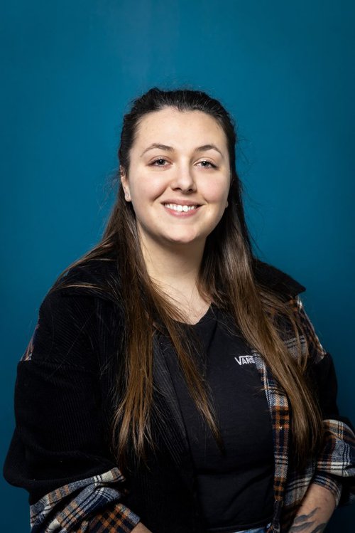 A headshot image of a young woman with dark hair smiling to the camera.