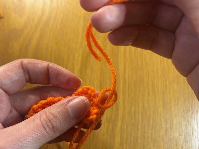 Tying a knot in a tail of yarn on a knitting project