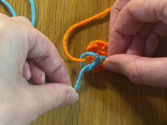 Tying a second piece of yarn onto a yarn tail in a knitting project