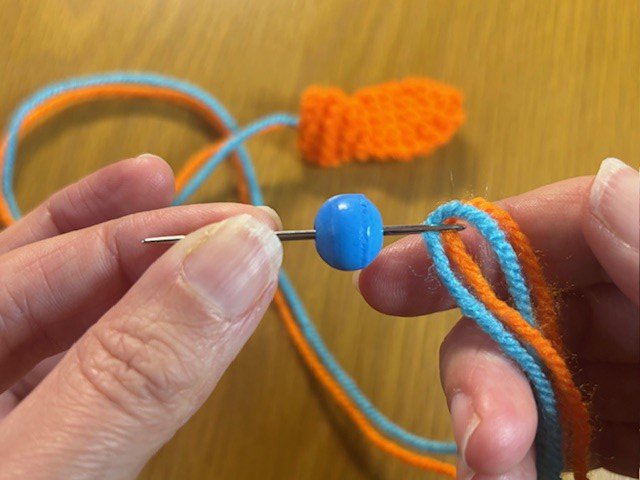 Threading a bead onto two pieces of yarn