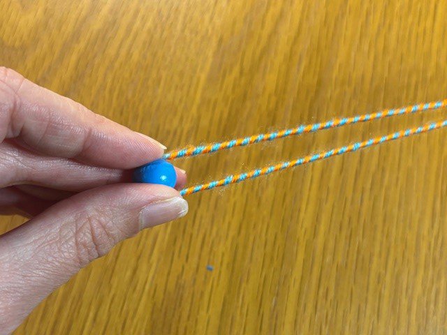 Twisted string folded in half around a wooden bead