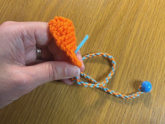 Small knitted fish bookmark on a twisty string