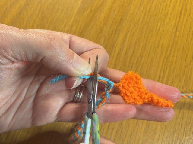 A pair of scissors trimming the loose ends of a twisty string