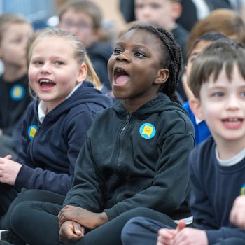 Children in school uniform sat on the floor, smiling