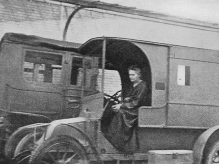 Black and white photo of a woman driving an old fashioned truck