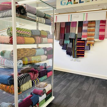 A display of scarves on a wall and on a glass display shelf