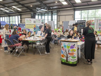 People having a go at craft activities at an event with a backdrop of colourful exhibition materials