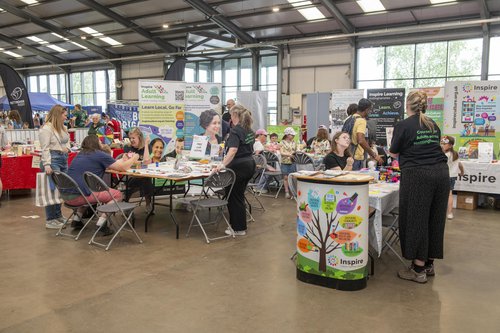 People having a go at craft activities at an event with a backdrop of colourful exhibition materials