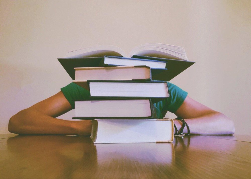 Pile of books obscuring reader