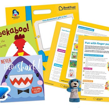 Two baby board books, one title Peekaboo! and one Never Feed a Shark next to shark and bear finger puppet and information leaflets.