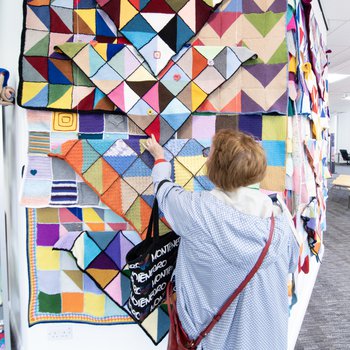 A person looks at the exhibition wall of blankets