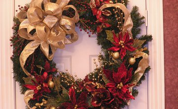 A christmas wreath hanging on a white door with red flowers