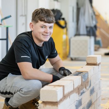 Young male student learning bricklaying at college