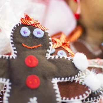 A handsewn gingerbread man decoraton with buttons and a pompom on his hand