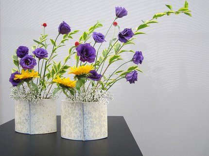 A stone like round container with purple and yellow flowers with green foliage