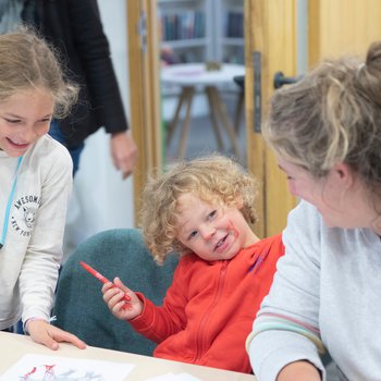 Children and adult doing a craft activity, smiling