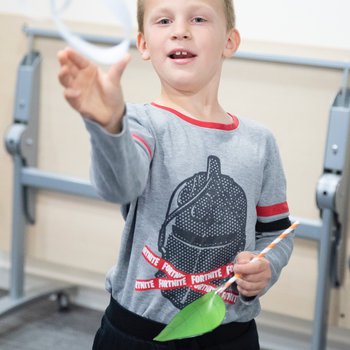 Child with paper glider and leaf wand