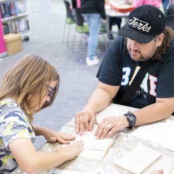 Man and child doing a book folding activity