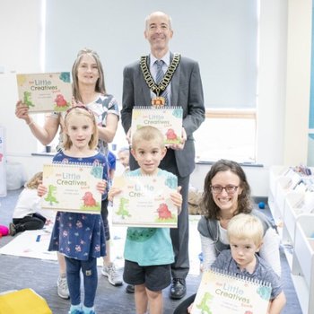 Vice Chair of Nottinghamshire County Council, Councillor Richard Butler, a Little Creatives artist, and a family all holding up copies of the newly launched Little Creatives book