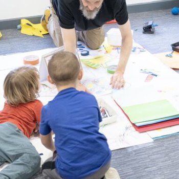 2 young children taking part in a floor-based creative activity with a Little Creatives artist