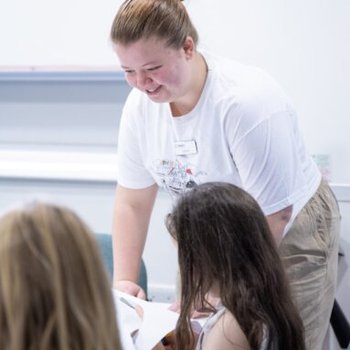 A Fun Palace volunteer helping 2 young girls with an activity