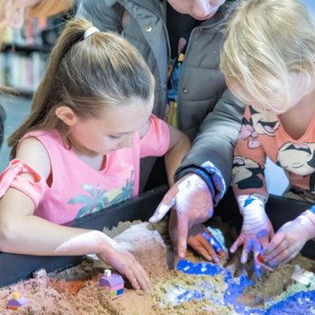 Young girls playing with objects in an illuminated sand tray