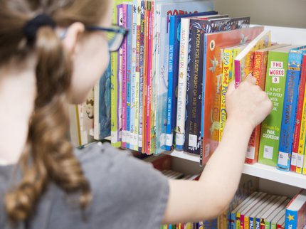 girl picking book off shelf.jpg